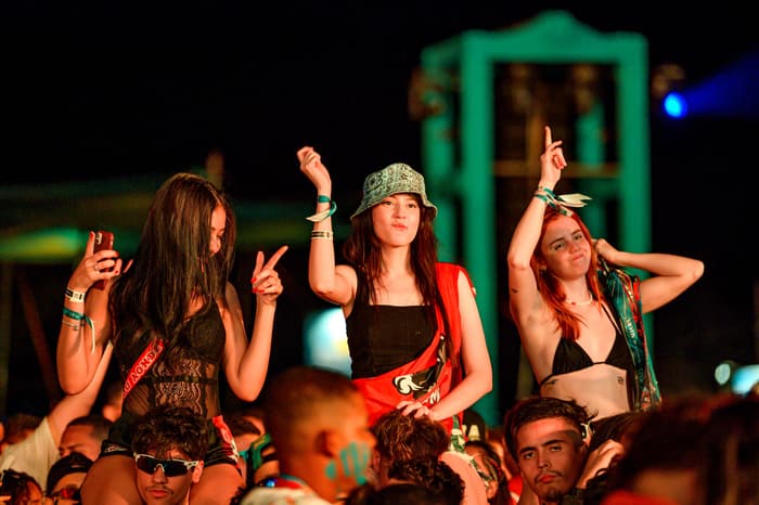 Three guests dancing at the front of a festival stage