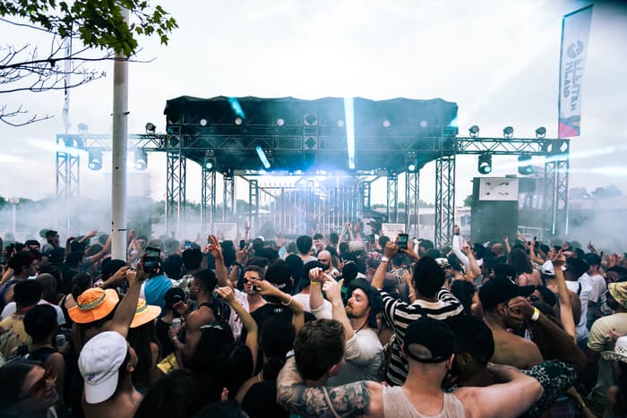 A festival crowd in front of a smoky stage