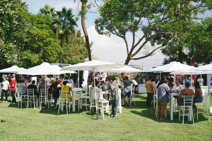 Guests at tables under white umbrellas on a lawn